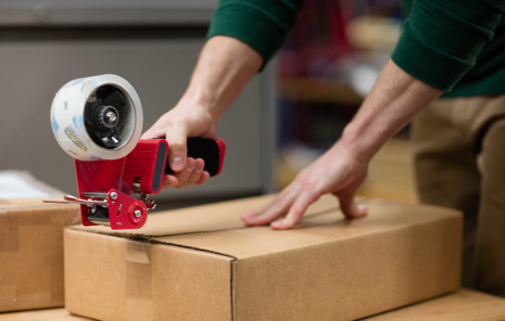 Person using a tape gun to seal a box closed